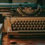 Close-up of a vintage typewriter on a wooden desk with classic design elements. Blog post on technology and progress.